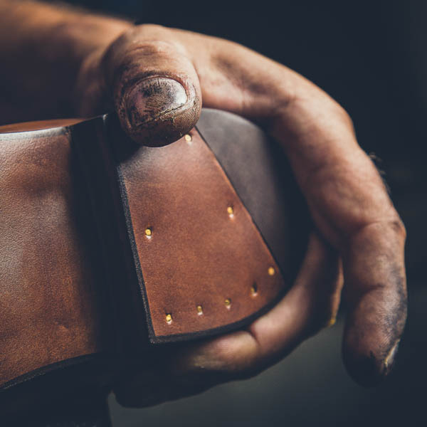 Reportage corporate sur Bordeaux dans l'atelier d'un cordonier. Détail d'un main travaillant le cuir d'un chaussure haut de gamme.