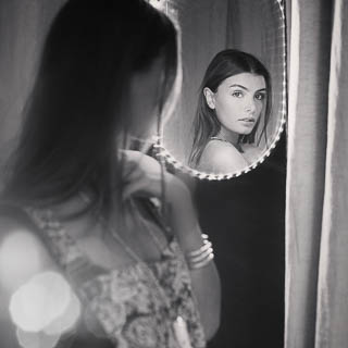 Photo en noir et blanc d'une jeune femme se reflétant dans un miroir