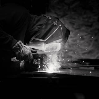 Photo en noir et blanc d'un ouvrier travaillant le métal réalisée par un photographe professionnel à Bordeaux