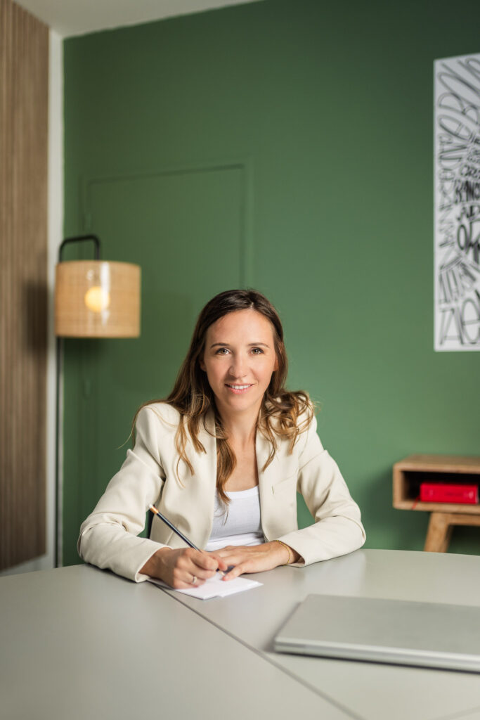 Portrait en situation dans les bureaux du client : femme souriante à sa table de travail
