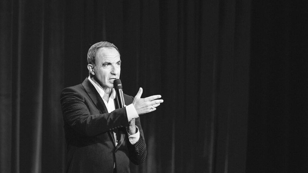 Intervenant s'exprimant au micro lors d'une conférence, portrait en noir et blanc